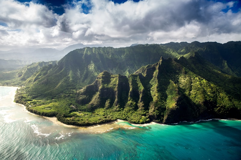 Dramatic aerial view of the Na Pali Coast in Kauai with emerald cliffs and turquoise ocean